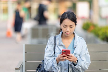 Foto de Mujer sentarse al aire libre y comprobar en el teléfono inteligente - Imagen libre de derechos