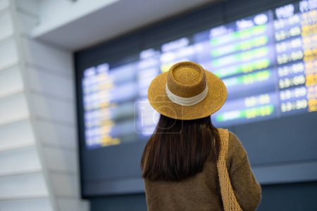 Foto de Mujer viajera mira el horario de vuelo en la pantalla - Imagen libre de derechos