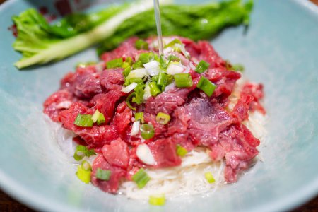 Téléchargez les photos : Soupe chaude bouillante verser dans une nouille avec une tranche de bœuf cru, cuisine célèbre à Kinmen de Taiwan - en image libre de droit