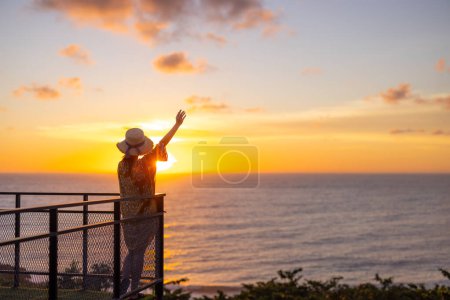 Téléchargez les photos : Femme touristique regarder le coucher du soleil vue sur la mer - en image libre de droit