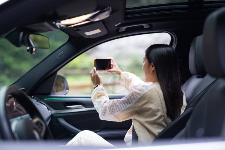 Téléchargez les photos : Femme utilisation de téléphone portable pour prendre des photos à l'intérieur de la voiture - en image libre de droit