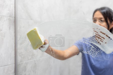 Foto de Mujer quitar manchas de agua dura y depósitos en el baño - Imagen libre de derechos