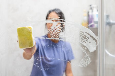 Téléchargez les photos : Femme enlever les taches d'eau dure et les dépôts dans la salle de bain - en image libre de droit