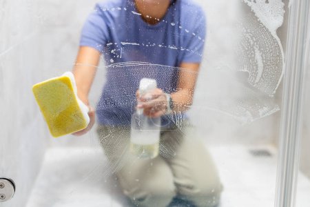 Photo for Woman remove hard water stains and deposits in bathroom - Royalty Free Image
