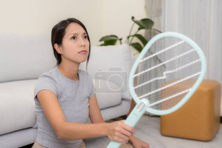 Foto de Woman use mosquito swatter at home - Imagen libre de derechos