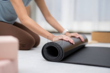 Foto de Mujer mano roll up yoga mat en casa - Imagen libre de derechos