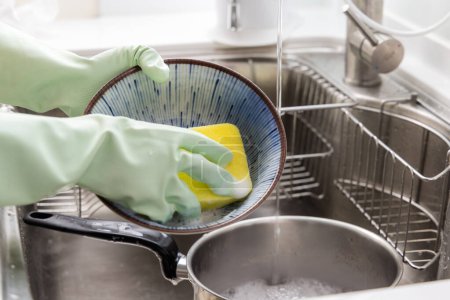 Téléchargez les photos : Femme au foyer laver le plat à la cuisine - en image libre de droit