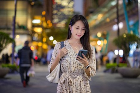 Foto de Mujer caminar por la calle y el uso del teléfono móvil por la noche - Imagen libre de derechos