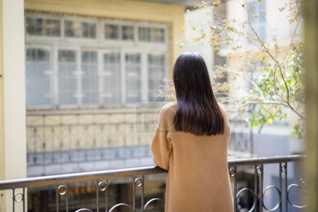 Téléchargez les photos : Femme profiter regarder la vue à l'extérieur du balcon - en image libre de droit