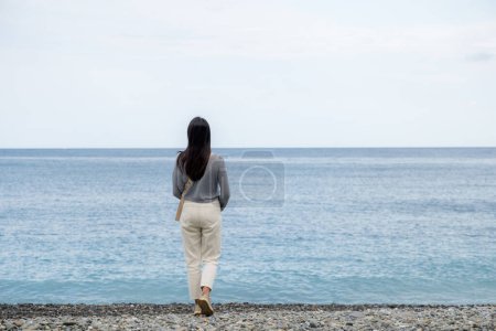 Foto de Mujer caminar por la playa de piedra - Imagen libre de derechos