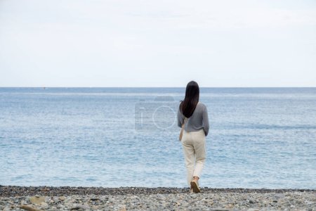 Foto de Mujer caminar por la playa de piedra - Imagen libre de derechos