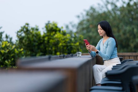 Téléchargez les photos : Femme utiliser un téléphone mobile et s'asseoir à l'extérieur du café - en image libre de droit