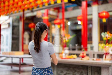 Téléchargez les photos : Femme tenant des bâtons d'encens fumant dans le temple chinois - en image libre de droit