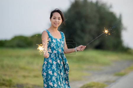 Photo for Woman play with beautiful sparkler burning at outdoor - Royalty Free Image