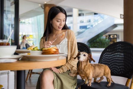 Photo for Woman bring her dachshund at outdoor restaurant - Royalty Free Image