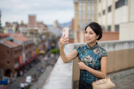 Foto de Mujer llevar cheongsam y utilizar el teléfono móvil para tomar la foto - Imagen libre de derechos
