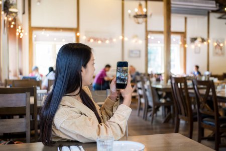 Foto de Mujer utilizar el teléfono celular para tomar fotos en el restaurante - Imagen libre de derechos