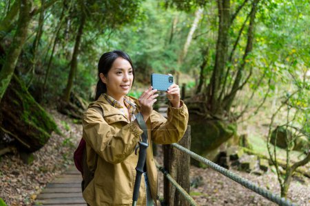 Foto de Mujer utilizar el teléfono celular para tomar fotos en el senderismo forestal - Imagen libre de derechos