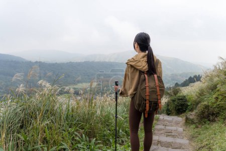 Téléchargez les photos : Femme faire de la randonnée avec bâton de trekking et marcher à travers la montagne - en image libre de droit