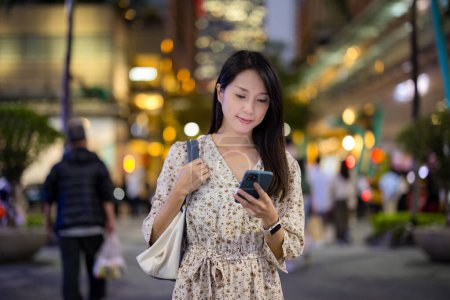 Photo for Woman use mobile phone in Taipei city at night - Royalty Free Image