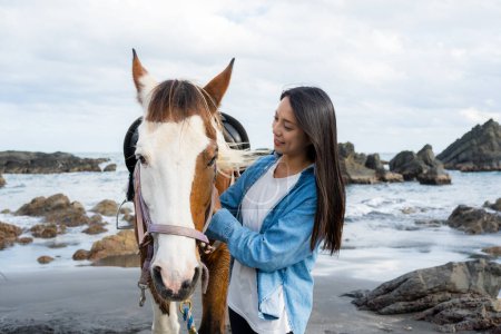 Photo for Tourist woman cuddle a horse at the sea beach - Royalty Free Image