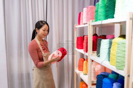 Téléchargez les photos : Femme choisir la couleur du fil pour la fabrication de tapis tufting au studio - en image libre de droit