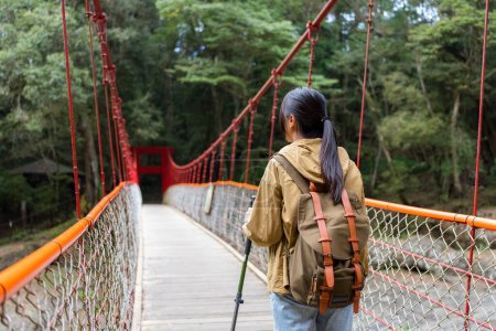 Foto de Mujer ir de excursión y caminar a lo largo del puente colgante - Imagen libre de derechos