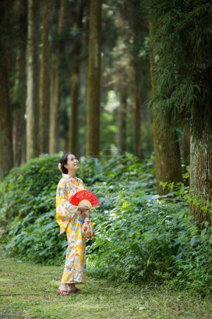 Foto de Mujer asiática tratar de usar kimono japonés en el bosque de bambú - Imagen libre de derechos