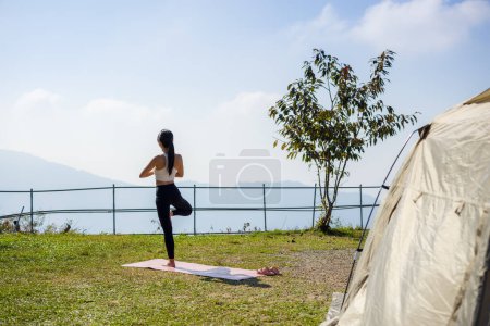 Photo for Woman do yoga exercise in camp site with camping tent - Royalty Free Image