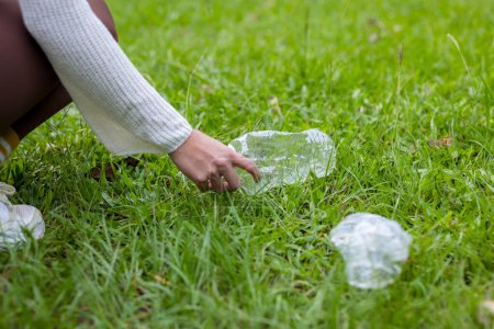 Photo for Woman hand collect plastic bottle from grass - Royalty Free Image