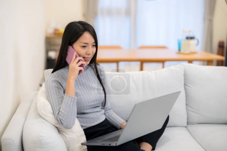 Téléchargez les photos : Femme travail sur ordinateur portable et parler au téléphone portable à la maison - en image libre de droit