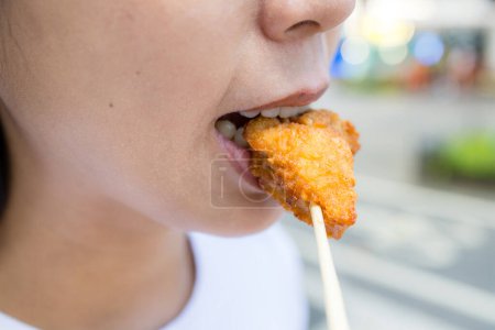 Foto de Mujer comer con pedazo de pollo crujiente - Imagen libre de derechos