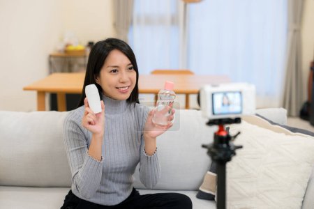 Téléchargez les photos : Femme prendre la vidéo pour vendre le produit cosmétique à la maison - en image libre de droit