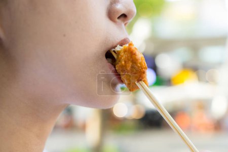Photo for Woman eat with piece of the crispy chicken - Royalty Free Image