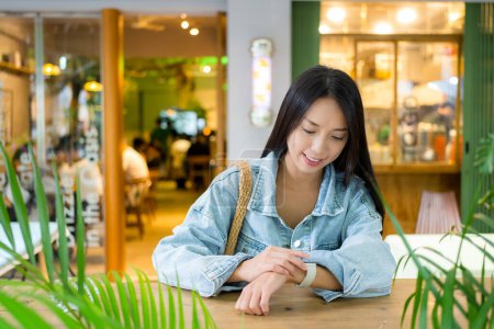 Téléchargez les photos : Femme regardez la montre intelligente dans un café confortable - en image libre de droit