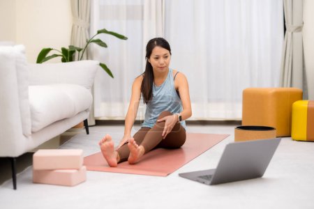 Foto de Mujer en casa hacer ejercicio de yoga con su ordenador portátil - Imagen libre de derechos
