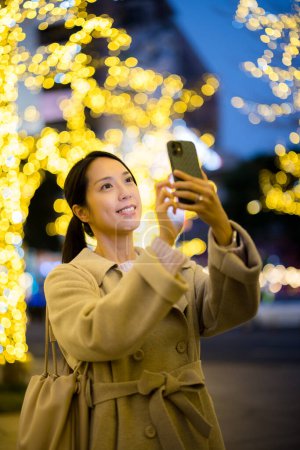 Foto de Mujer utilizar el teléfono móvil para tomar fotos en la ciudad por la noche - Imagen libre de derechos