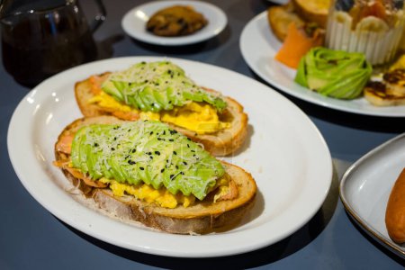 Téléchargez les photos : Avocat tranché sur pain grillé au saumon avec des épices - en image libre de droit