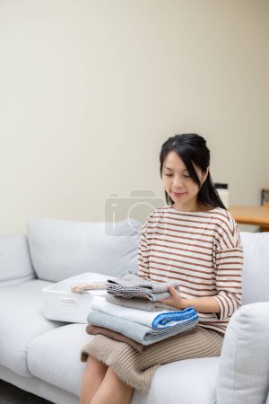 Téléchargez les photos : Femme au foyer plier avec la serviette lavée après la lessive à la maison - en image libre de droit