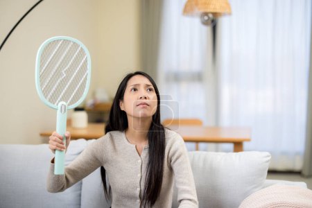 Photo for Woman use mosquito swatter at home - Royalty Free Image