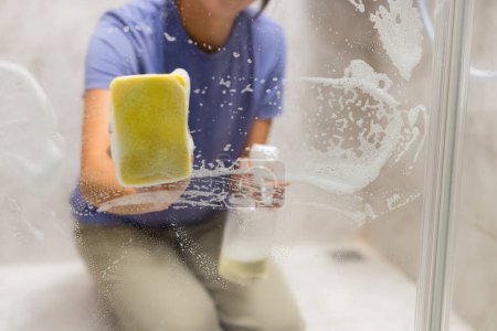 Téléchargez les photos : Éponge nettoyer le verre des fenêtres dans la salle de bain - en image libre de droit