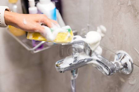 Téléchargez les photos : Nettoyage des taches d'eau dure dépôts sur le robinet de bain aux toilettes - en image libre de droit