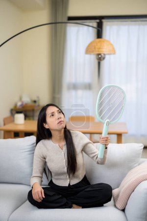 Photo for Woman use mosquito swatter at home - Royalty Free Image