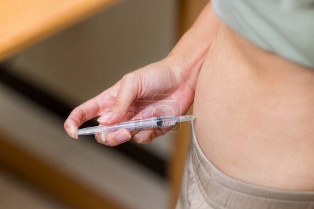 Téléchargez les photos : Femme injecte des hormones dans le ventre avec une seringue - en image libre de droit