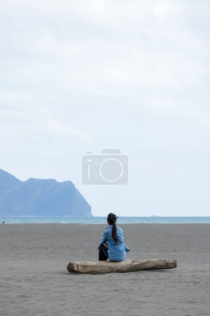 Foto de La mujer se sienta en la playa y mira el Guishan en Yilan - Imagen libre de derechos