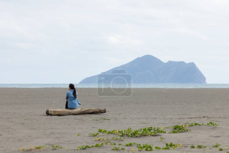 Woman sit on the beach and look at the Guishan at Yilan