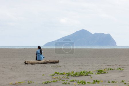 Photo for Woman sit on the beach and look at the Guishan at Yilan - Royalty Free Image