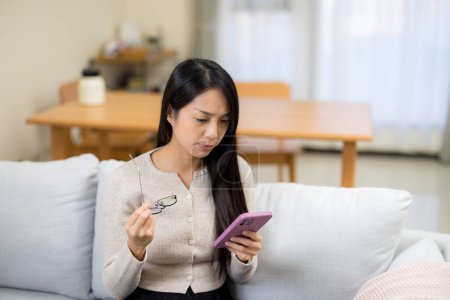 Femme souffrant de fatigue oculaire en essayant de lire sur un téléphone portable à la maison