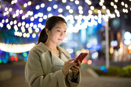 Téléchargez les photos : Femme utiliser le téléphone portable dans la ville la nuit - en image libre de droit