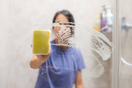 Téléchargez les photos : Femme nettoyer les taches d'eau dure et les dépôts dans la salle de bain - en image libre de droit